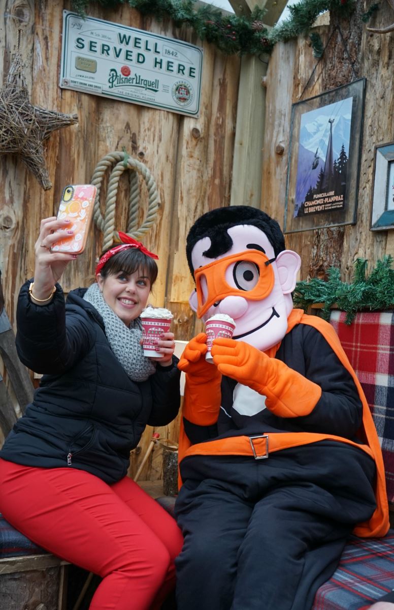 At Bournemouth's SKATE ice-rink, a young woman takes a selfie with a super-hero mascot dressed in black with an orange cape